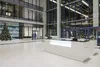 Ресепшн Хибины белый с LED-нишей в просторном лобби, вид сбоку, дневное освещение.